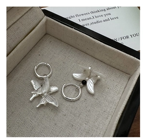 Detail of silver butterfly hoop earrings with white shell wings on linen jewelry box