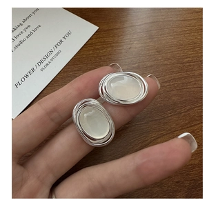 Dettaglio ravvicinato di orecchini ovali in argento con pietre di agata tra le dita
