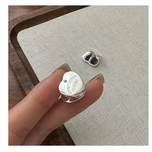 Macro shot of silver heart earring featuring Expectation and Future engravings