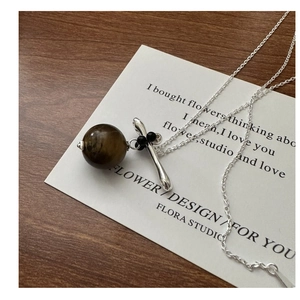 Gros plan d'un collier en argent S925 avec pendentif œil de tigre sur fond de bois sombre
