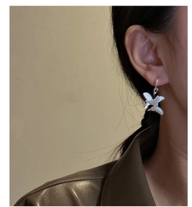 Detail of S925 silver butterfly earrings with white shell wings on a female model