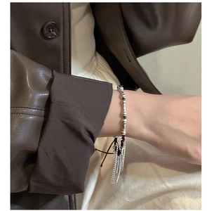 Close-up of S925 silver beaded tassel bracelet worn over stylish leather and beige clothing