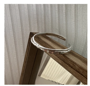 Detailed macro view of S925 sterling silver stamp on the textured minimalist open bangle
