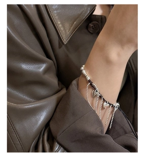 Close-up of S925 silver tassel heart bracelet with black woven rope on wrist