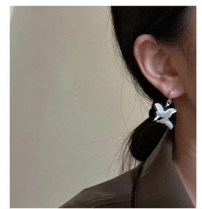 Detailed close-up of a pearlescent white butterfly earring worn by a model