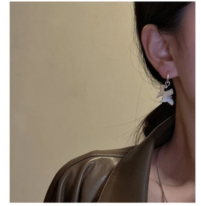 Close-up of butterfly drop earrings with white shell detail on a model's ear