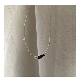 Close-up of S925 silver necklace featuring dark mineral stones on pleated fabric