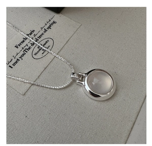 Macro detail of S925 silver necklace with a minimalist round white agate stone pendant