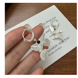 Detail of S925 silver butterfly earrings with white shell drop on a wooden desk