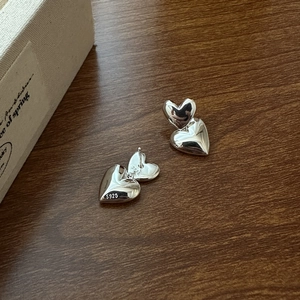 Polished S925 sterling silver double heart stud earrings on a wooden background
