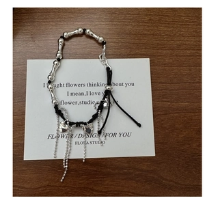 Detail of S925 silver heart tassel bracelet with bamboo beads and black cord on card