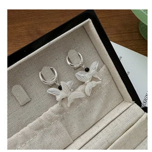 Macro view of butterfly earrings with white resin wings in a beige jewelry box
