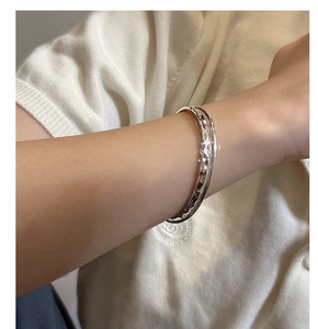 Detailed close-up of a silver hammered texture open cuff bracelet on a female wrist