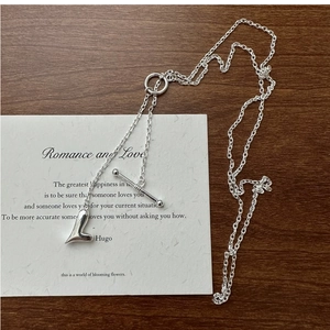 Dettaglio della collana a cuore in argento con chiusura a T su sfondo in legno