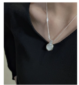 Detail shot of a minimalist S925 sterling silver necklace with a round white agate stone