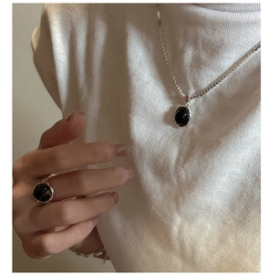 Détail du collier et de la bague en argent S925 avec onyx noir ovale sur tricot blanc
