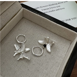 Detail view of S925 silver butterfly earrings with white shell wings in a jewelry box