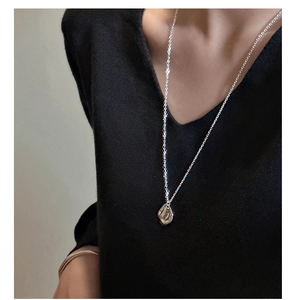 Gros plan du collier en argent sterling S925 avec pendentif texturé sur un pull noir
