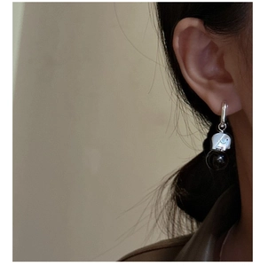 Macro shot of a silver elephant earring with a dark translucent bead on a female model