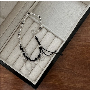 Detail of S925 silver fringe heart bracelet with black cord in a beige velvet jewelry box