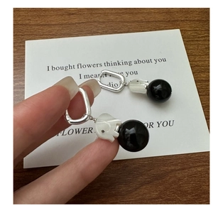Detailed close-up of elephant agate earring with silver buckle and black polished ball drop