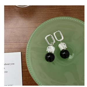 Detail of silver elephant earrings with black beads on a green glass tray background