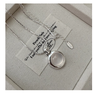 Macro view of S925 sterling silver chain with a polished round white agate stone pendant