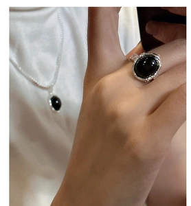 Close-up of S925 silver ring with black onyx and silver hammered texture on white satin