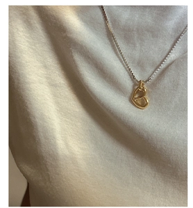 Close-up of a two-tone sterling silver heart pendant necklace on a person wearing white