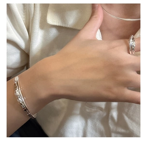 Detail of S925 sterling silver bangle and rings set with unique fluid metal texture