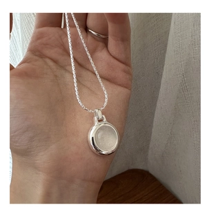 Close-up of a minimalist S925 sterling silver necklace with a round white agate pendant
