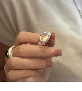 Detail of S925 sterling silver ring with oval moonstone on model's hand in soft light