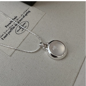 Detail view of S925 sterling silver necklace with a round white agate stone on linen fabric