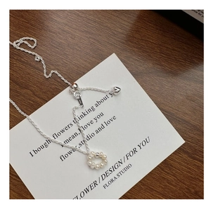 Detail of S925 sterling silver chain with heart charm and woven pearl circle pendant