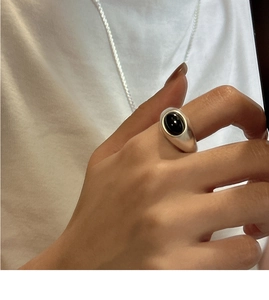 Close-up of a S925 sterling silver ring with black oval agate on a hand, minimalist style