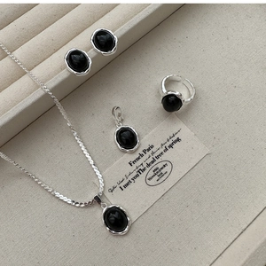 Macro shot of S925 silver jewelry set with black onyx pendants on a beige tray