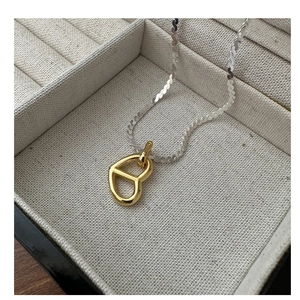 Detail of S925 silver snake chain with a gold geometric heart-shaped pendant