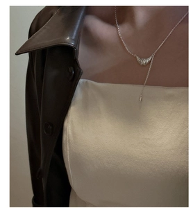 Détail du collier croissant en argent avec texture plissée porté par un mannequin
