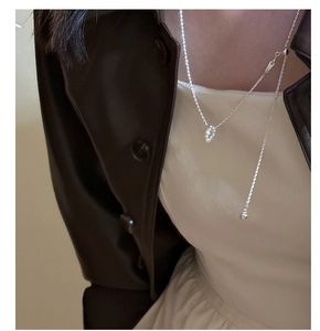 Detail of S925 silver baroque pearl necklace worn over a stylish brown leather jacket