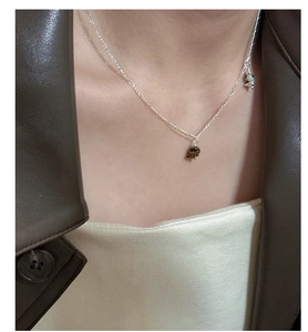 Detail of S925 silver necklace with tiger eye and marble beads on a model wearing leather