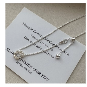 Detail of S925 silver chain with baroque pearl ring pendant and heart charm on white card