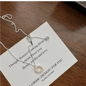 Macro shot of S925 silver necklace with pearl wreath pendant and heart-shaped charm