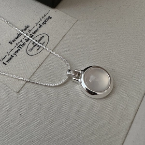 S925 sterling silver necklace with a round white agate stone pendant on linen surface
