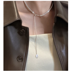 Close-up of S925 sterling silver necklace with textured round pendant on model