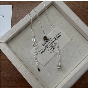 Detailed close-up of S925 sterling silver Figaro chain with tiger eye stone pendant