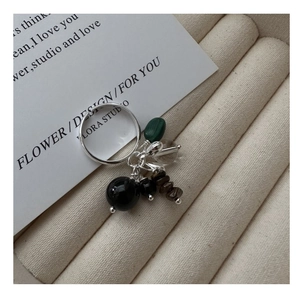 Close-up of S925 silver ring featuring natural stone charms on beige velvet tray