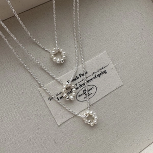 Three S925 silver baroque pearl necklaces arranged on textured beige linen background