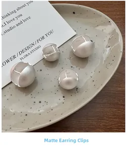 Dettaglio orecchini a sfera in argento S925 opaco con marchio su vassoio di ceramica
