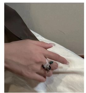 Detail of S925 silver ring featuring green teardrop and irregular clear charms on a hand