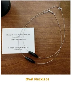 Detail of S925 silver necklace with black oval bead and T-bar toggle clasp on wood